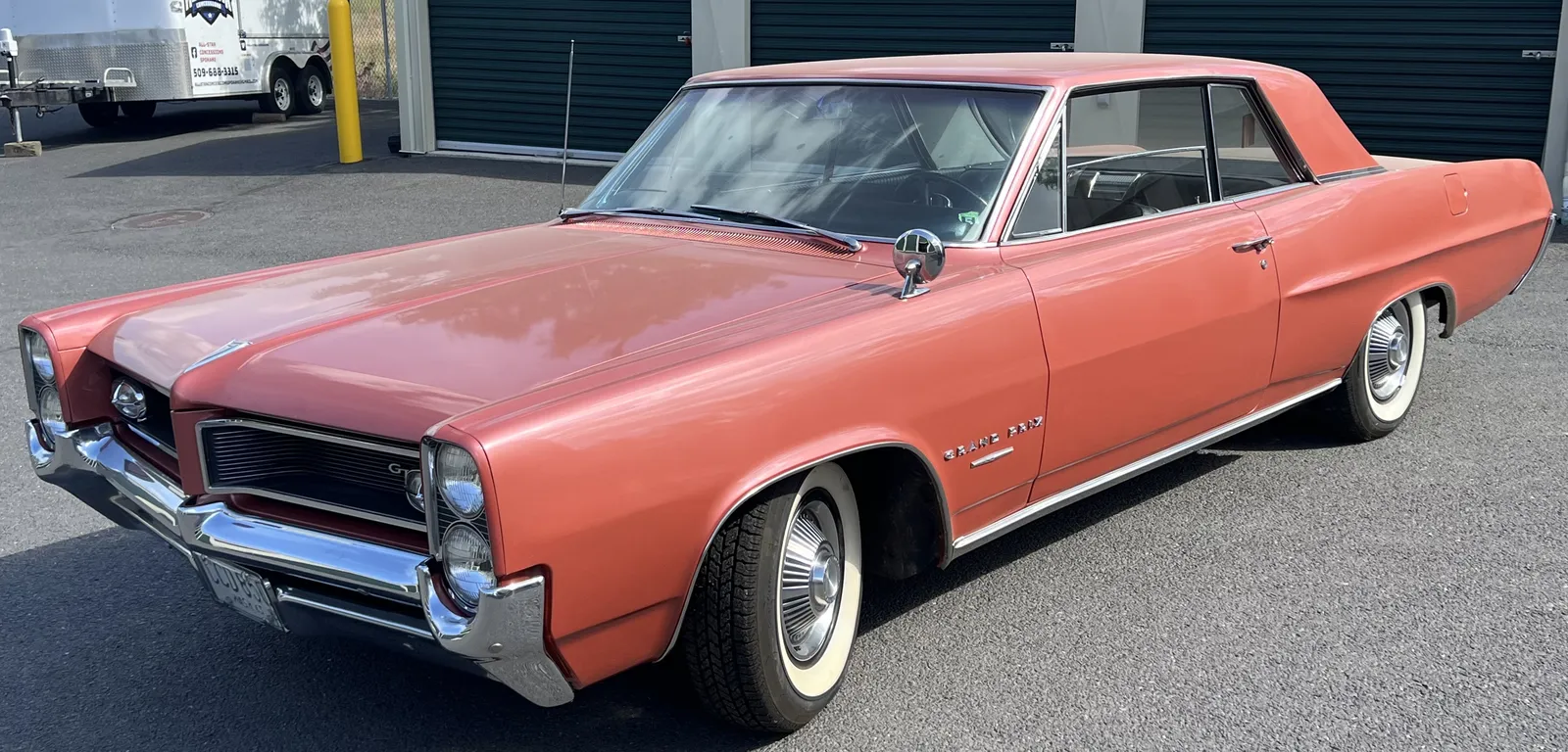 1964 Pontiac Grand Prix in salmon red parked outside after being serviced