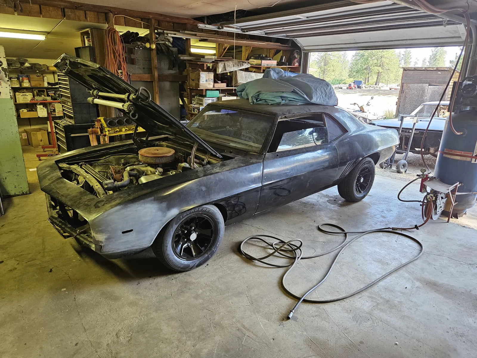 Classic coupe with the hood open in a garage bay during on-site service