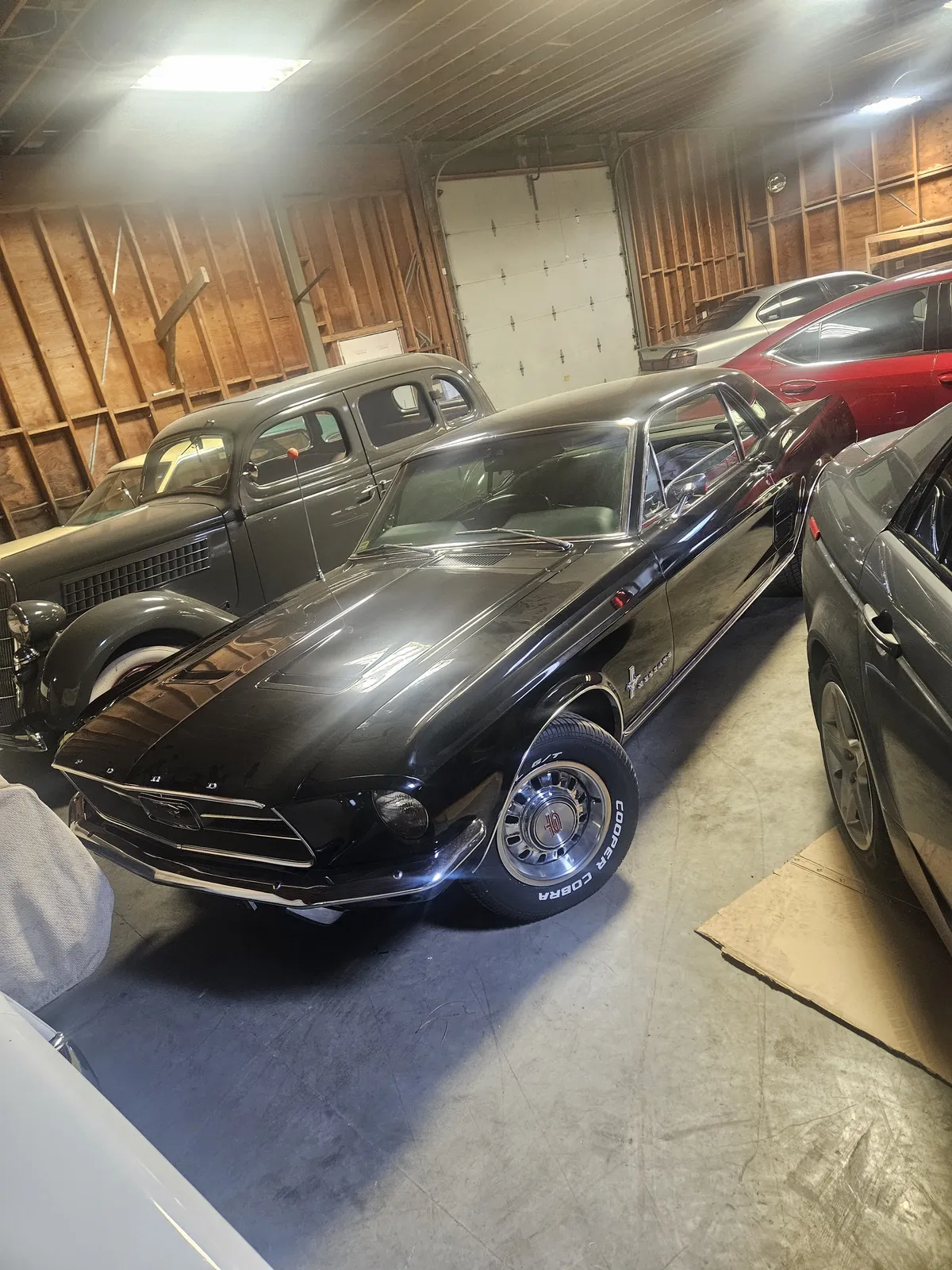 Two classic cars stored side by side in a shop during ongoing projects
