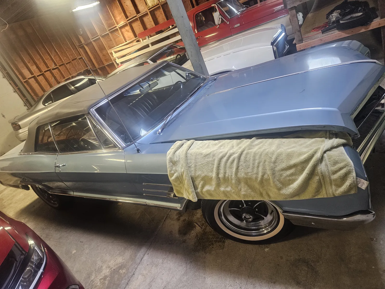 Silver Pontiac partially covered in a garage between stages of a build